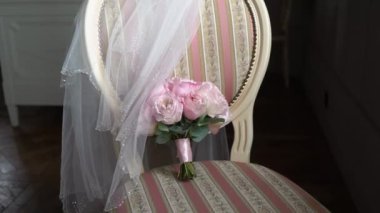 Bir buket pembe gül. Gelinin düğün buketi. Yeni evlilerin sabah hazırlıkları. Çiçek aranjmanı yatak odasında bir sandalyede - çiçekler ve peçe.