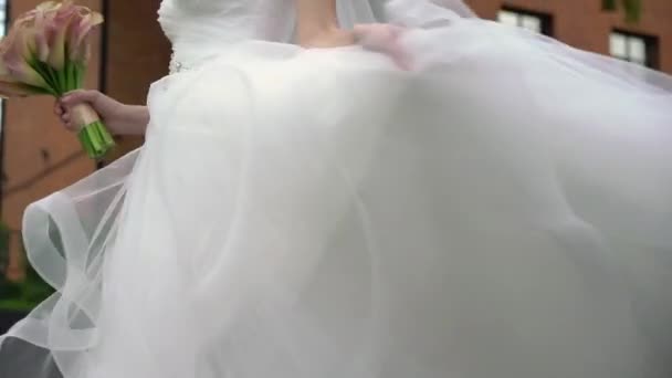 Νεαρή νύφη με νυφικό να κάνει κύκλους σε μια πόλη. Λευκή μόδα φόρεμα πολυτελείας — Αρχείο Βίντεο