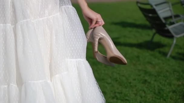 एक पार्क में चलने वाली शादी की पोशाक में युवा दुल्हन। सफेद लक्जरी पोशाक फैशन — स्टॉक वीडियो