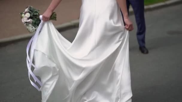 Молодая невеста в свадебном платье кружит в городе. Мода на белое платье — стоковое видео