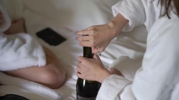 Las niñas abren una botella de champán y vierten las copas en casa. Bebidas alcohólicas y bebidas . — Vídeo de stock