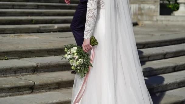 Unga bröllopspar går nära palatset i parken. Brud och brudgum i lyx kunglig plats uppför trappan — Stockvideo