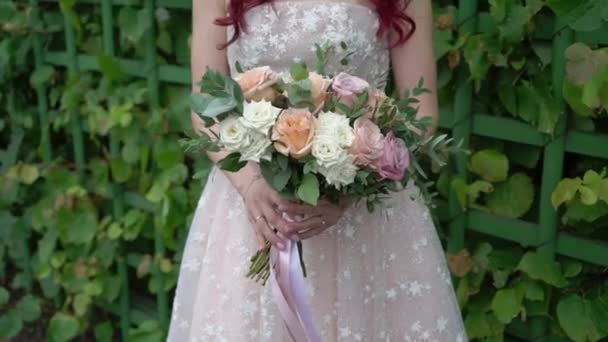 Młoda panna młoda w sukni ślubnej trzymająca kwiaty bukietu w parku. Biały luksusowy strój mody — Wideo stockowe