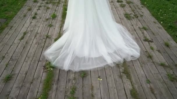 Молода наречена у весільній сукні ходить у парку. Біла розкішна мода сукні — стокове відео