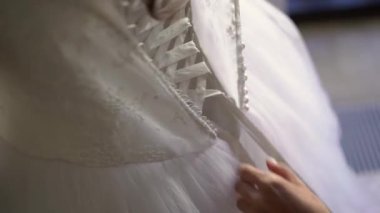 Nedime, genç gelinin gelinliğini giymesine yardım ediyor. Lüks gelinlik.