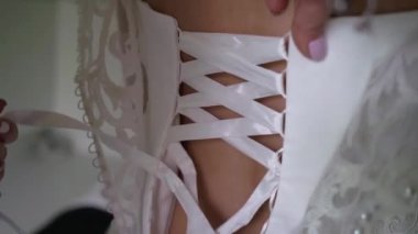 Nedime, genç gelinin gelinliğini giymesine yardım ediyor. Lüks gelinlik.