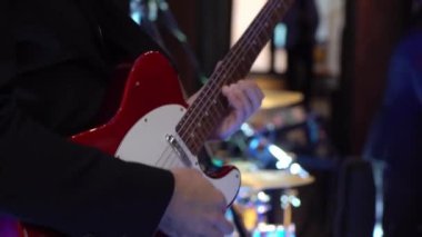 Gitarist konserde gitar çalıyor. Sahnede telli enstrümanlı müzisyen.