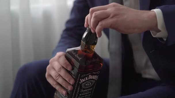 ロシアのサンクトペテルブルク- 8月19 、 2019:ウィスキーのボトルを持つ男Jack Daniels 。男性飲料アルコールバーボンまたはコニャック. — ストック動画