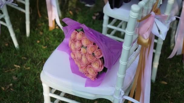Ceremonia de boda al aire libre. Ramo de flores en un asiento en una fila — Vídeo de stock
