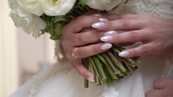 Jonge bruid in trouwjurk met boeket bloemen binnen. Witte luxe jurk mode — Stockvideo