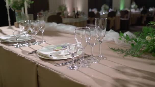 Bril, borden, bestek en servetten. Gedecoreerde tafels met bloemen voor het feest. Huwelijksreceptie, verjaardag, jubileum. — Stockvideo