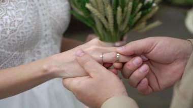 Gelin ve damat törende alyanslarını değiş tokuş ederler. Hoş bir çift.