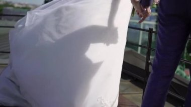 Gelin ve damat şehirde yürüyor. Genç ve güzel bir çift. Gelin çiçekleri buketi