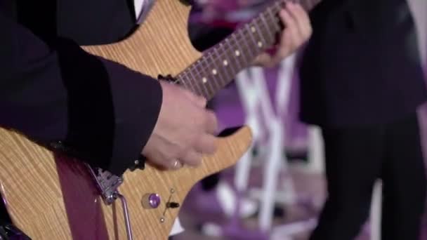 Kytarista hraje na kytaru na koncertě. Hudebník s smyčcovým nástrojem na pódiu. — Stock video