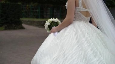 Genç bir çift parkta yürüyor. Gelin ve damat yazın