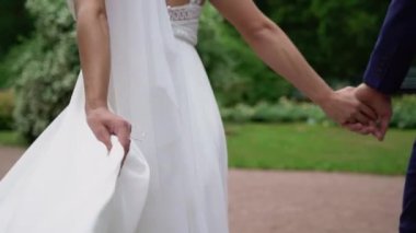 Genç bir çift parkta yürüyor. Gelin ve damat yazın