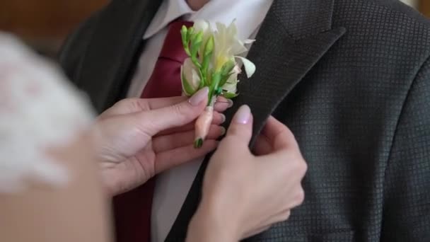 Bruden sätter på sig boutonniere för brudgummen. Förberedelse av bröllopsceremoni — Stockvideo