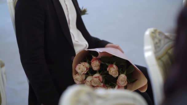 Hombre sentado con ramo de flores y esperando nervioso — Vídeos de Stock