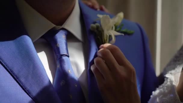 Kvinna hjälper till att sätta på och fixa slips. Brudgum i kostym med slips på bröllopsdagen — Stockvideo