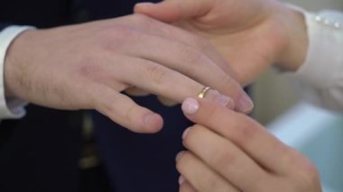 Gelin ve damat törende alyanslarını değiş tokuş ederler. Hoş bir çift.