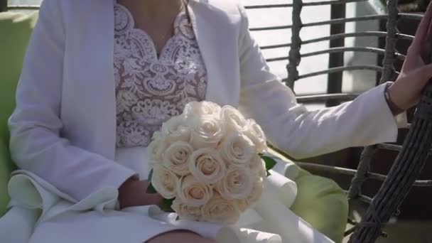 Young bride in wedding dress holding bouquet flowers in a park. White luxury gown fashion — Stock Video