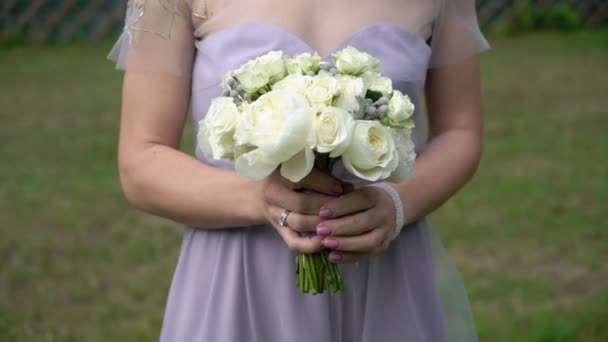 Mladá nevěsta ve svatebních šatech drží kytice květiny v parku. Bílé luxusní šaty móda — Stock video