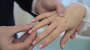 Gelin ve damat törende alyanslarını değiş tokuş ederler. Hoş bir çift.