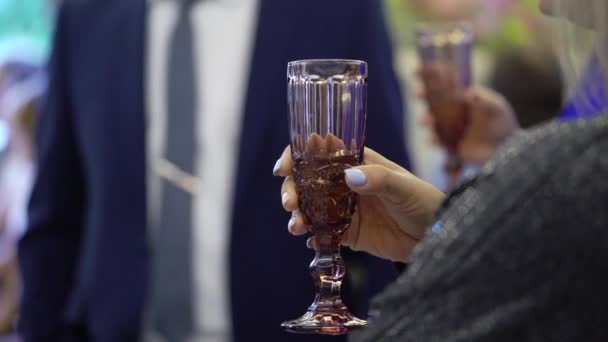 Pessoa segurando copo de vinho ou champanhe ou outra bebida alcoólica na mão na festa . — Vídeo de Stock
