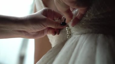 Nedime, genç gelinin gelinliğini giymesine yardım ediyor. Lüks gelinlik.