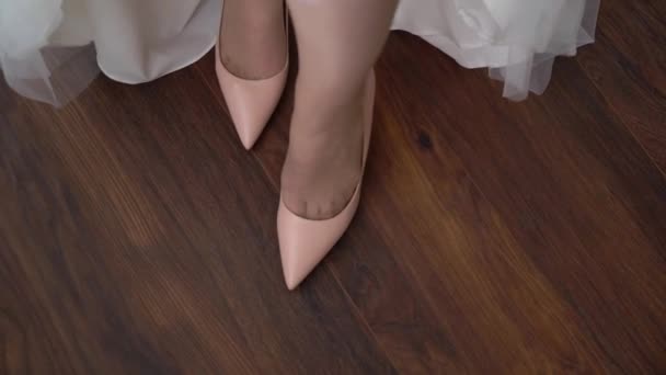 A jovem noiva calça sapatos nos saltos altos. Mulher moda sapatos brancos para o dia do casamento — Vídeo de Stock