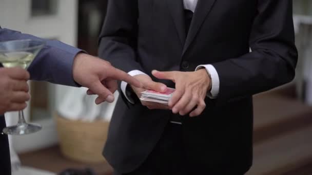 Kouzelník muž ukazující street magic trik s kartami. — Stock video