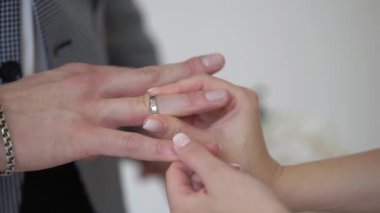 Gelin ve damat törende alyanslarını değiş tokuş ederler. Hoş bir çift.