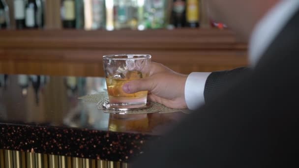 Muž se sklenicí whisky. Mužské pití alkoholu bourbon nebo koňak. — Stock video