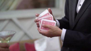 Sihirbaz adam kartlarla sokak sihirbazlığı numarası gösteriyor.