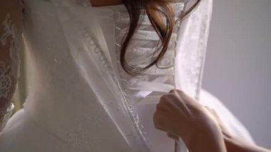 Nedime, genç gelinin gelinliğini giymesine yardım ediyor. Lüks gelinlik.