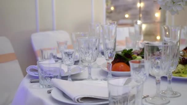 眼镜、盘子、餐具和餐巾装饰过的桌子上放着宴会用的花。婚宴、生日、周年纪念日. — 图库视频影像