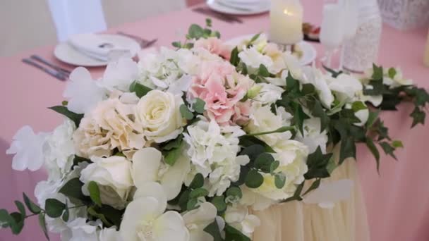 Bril, borden, bestek en servetten. Gedecoreerde tafels met bloemen voor het feest. Huwelijksreceptie, verjaardag, jubileum. — Stockvideo