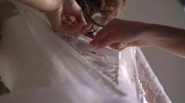 Nedime, genç gelinin gelinliğini giymesine yardım ediyor. Lüks gelinlik.