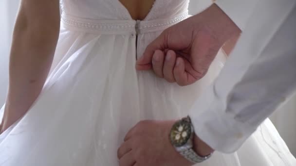 Demoiselle d'honneur aidant la jeune mariée à mettre sa robe de mariée. Robe de mariée de luxe — Video