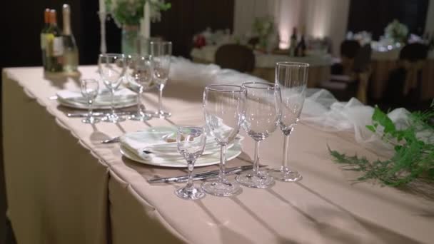 Очки, тарелки, столовые приборы и салфетки. Украшенные столы с цветами для вечеринки. Свадебный прием, день рождения, юбилей. — стоковое видео