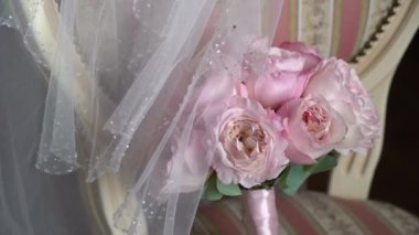 Bir buket pembe gül. Gelinin düğün buketi. Yeni evlilerin sabah hazırlıkları. Çiçek aranjmanı yatak odasında bir sandalyede - çiçekler ve peçe.