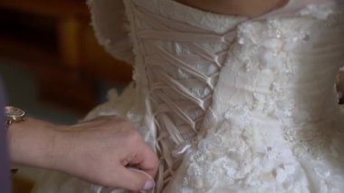 Nedime, genç gelinin gelinliğini giymesine yardım ediyor. Lüks gelinlik.