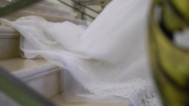 Beyaz gelinlikli genç gelin merdivenlerden iniyor.