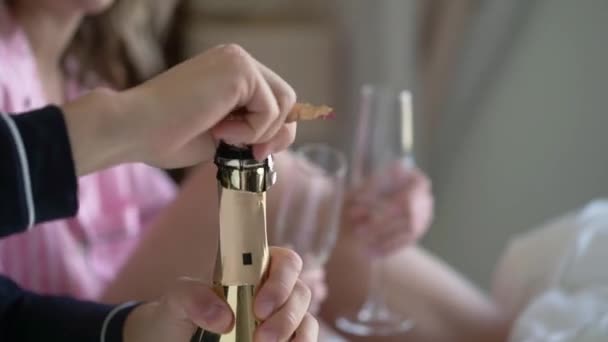 Een jong stel dat de fles champagne opent en thuis glazen inschenkt. Alcoholische dranken en dranken. — Stockvideo