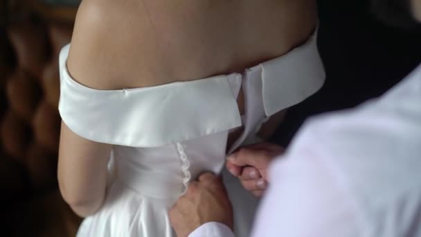 Bridesmaid helping for young bride to put on her wedding dress. Luxury bridal gown — Stock Video