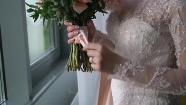 Молодая невеста в свадебном платье держит букет цветов в помещении. Мода на белое платье — стоковое видео