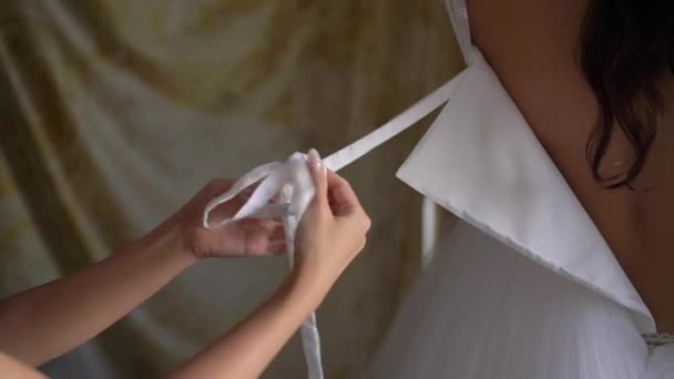 Druhna pomaga młodej pannie młodej założyć suknię ślubną. Luksusowa suknia ślubna — Wideo stockowe