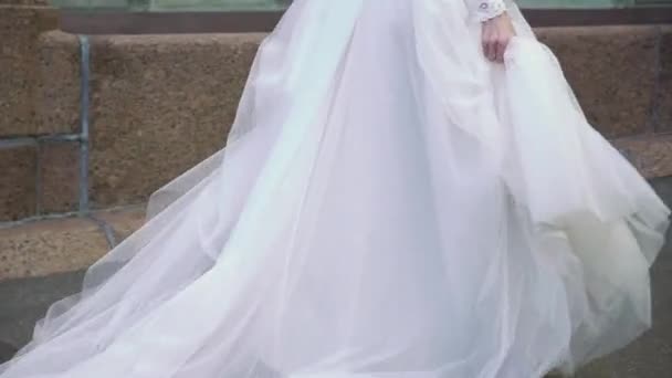 Giovane sposa in abito da sposa a piedi in una città. Bianco moda abito di lusso — Video Stock