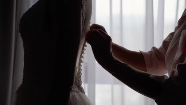 Družička pomáhá mladé nevěstě obléct si svatební šaty. Luxusní svatební šaty — Stock video