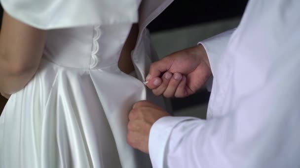 Demoiselle d'honneur aidant la jeune mariée à mettre sa robe de mariée. Robe de mariée de luxe — Video